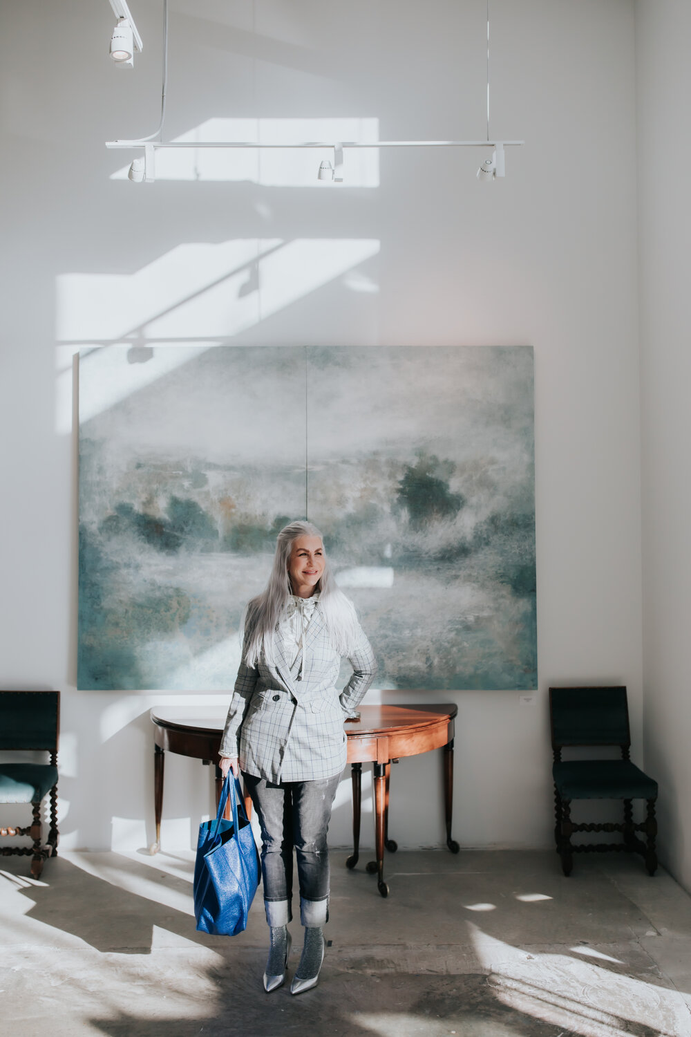 lisa in a gallery in atlanta wearing a tweed jacket with silver heels and socks with a blue bag