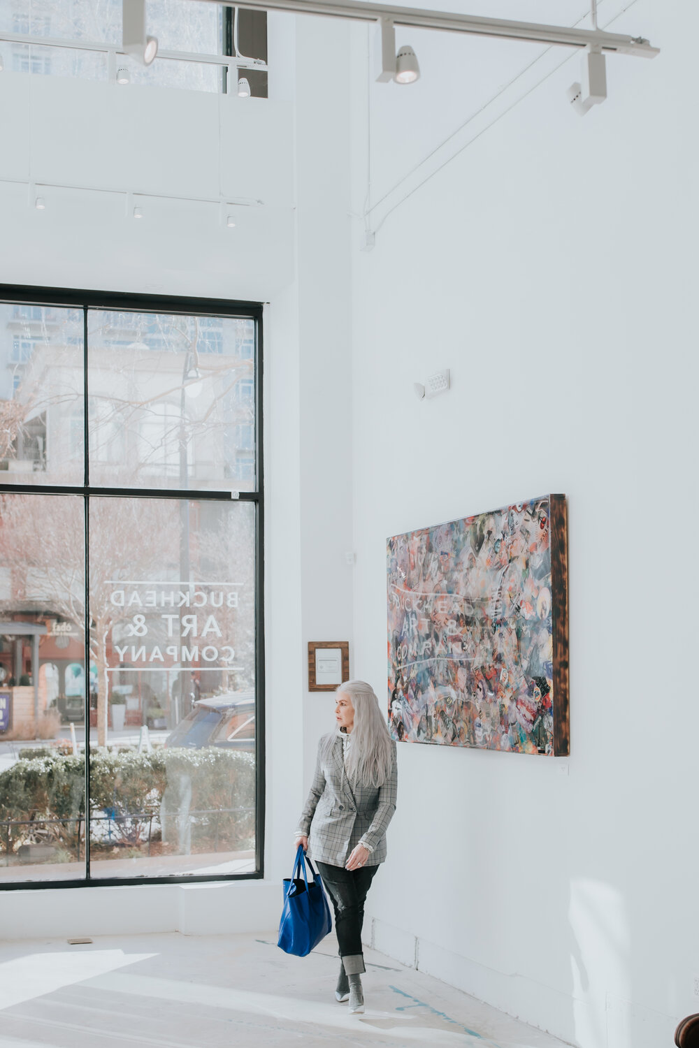 lisa in a gallery in atlanta wearing a tweed jacket with silver heels and socks with a blue bag