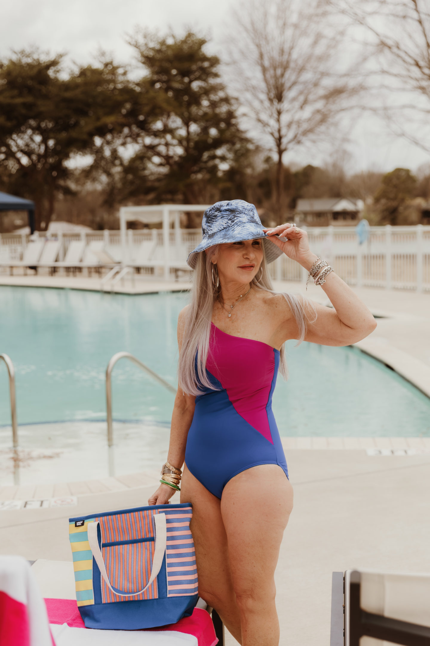 lady in one piece bathing suit wearing hat by the pool