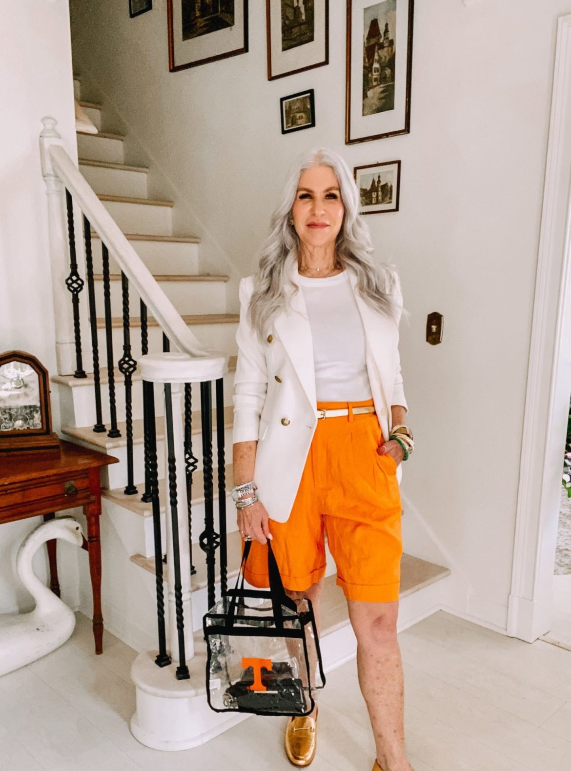 silver hair woman wearing orange shorts and white top and jakcket