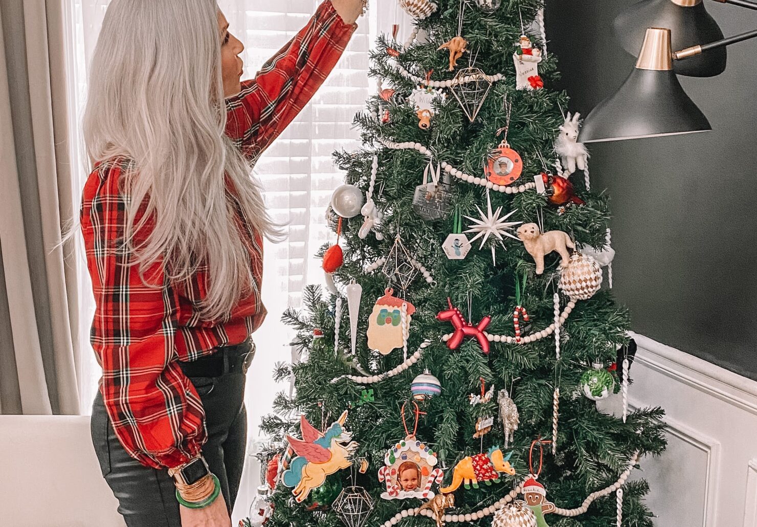 woman putting ornament on Christmas Tree