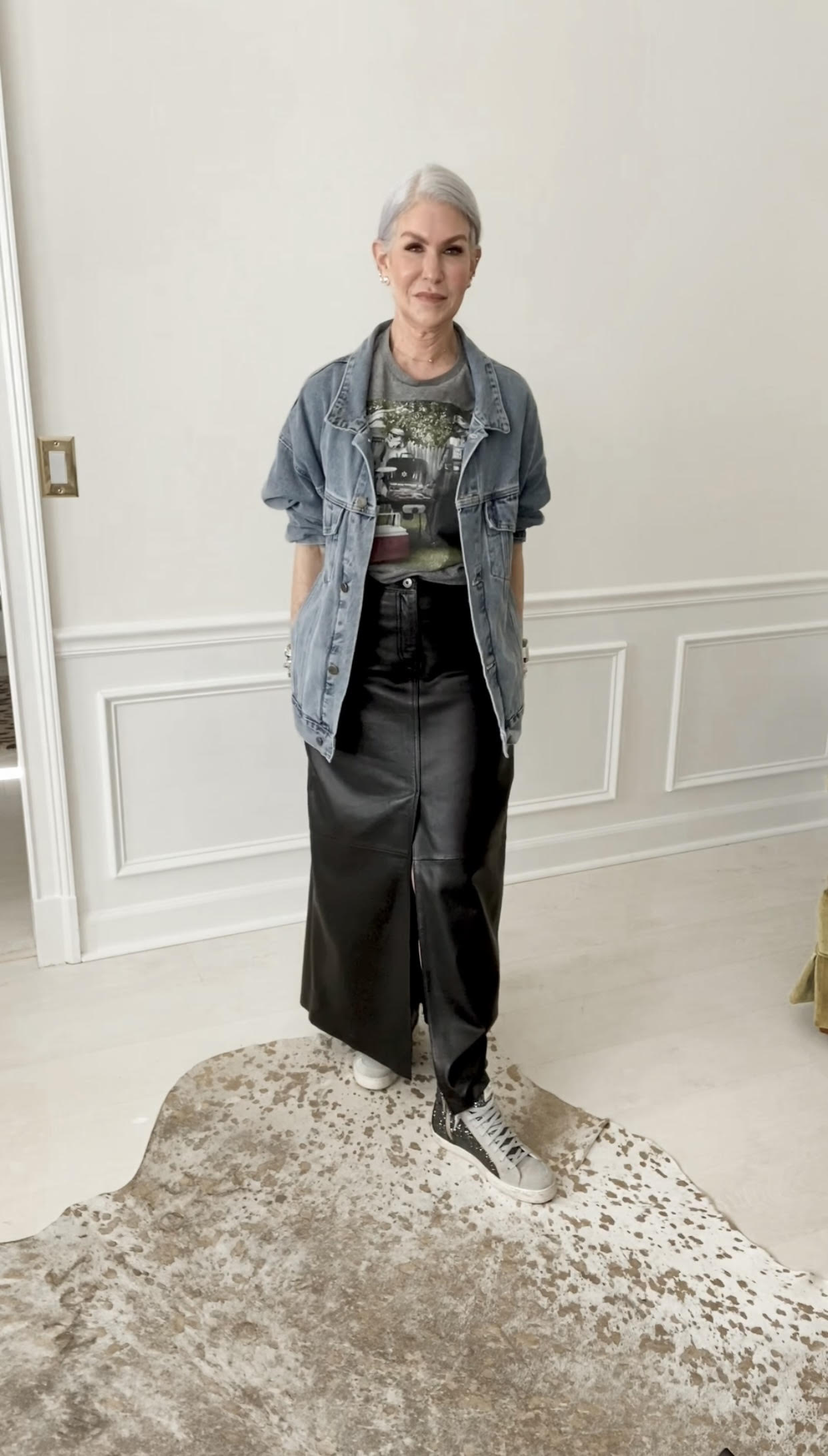 silver haired woman wearing long leather skirt with graphic tee and blue jean jacket