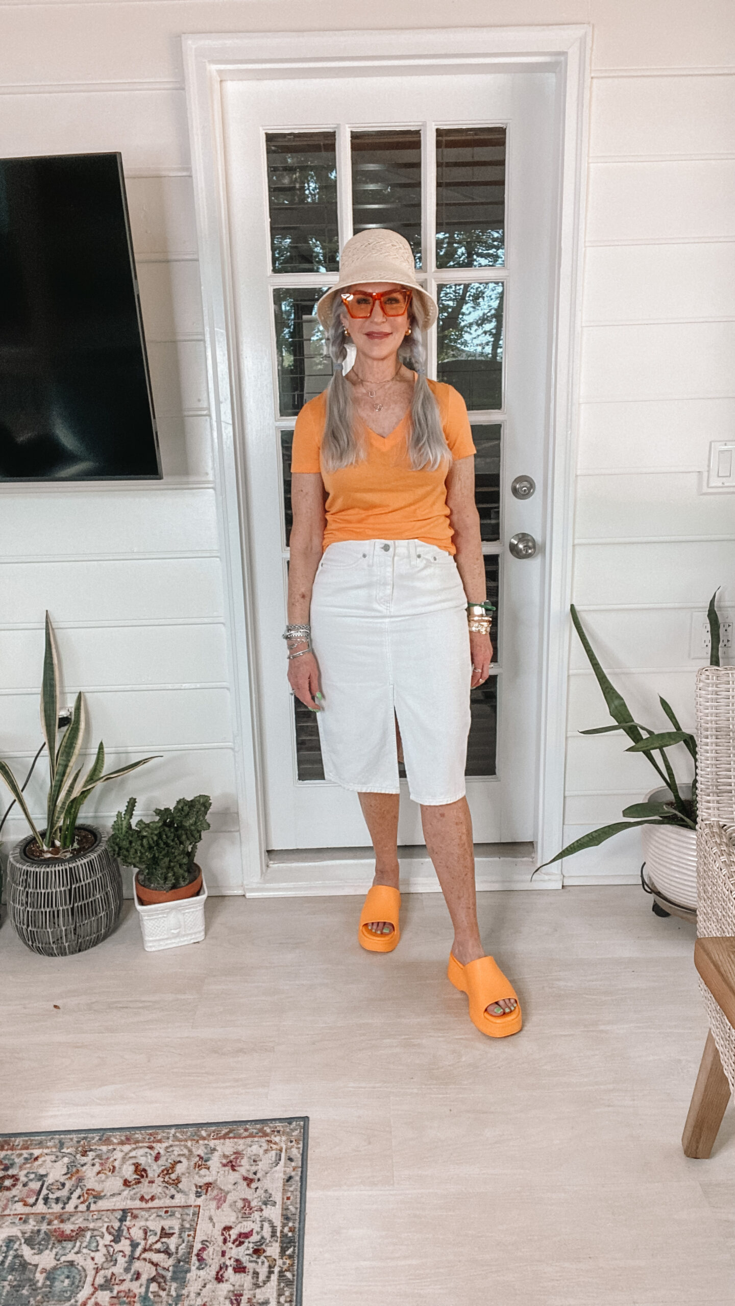 silver hair middle age woman wearing white denim skirt with orange shirt
